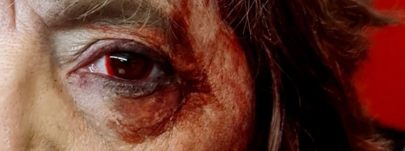 Maquillaje de caracterización FX en el ojo de un personaje herido con sangre simulada y texturas en la piel.